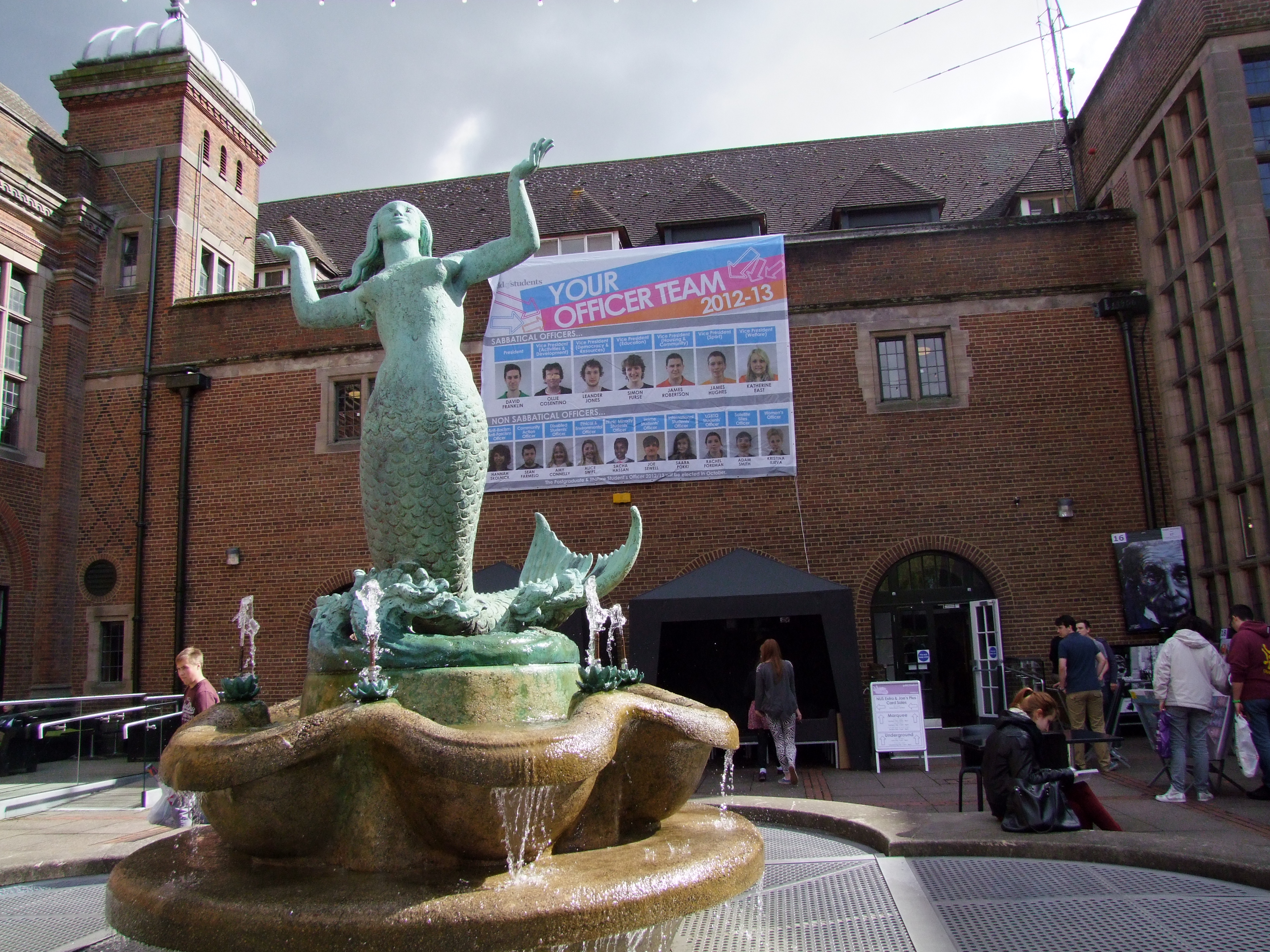 mermaid square with people and officer elections banner in the background