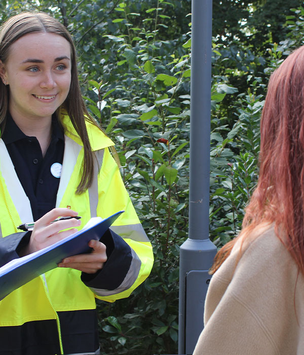 A student with a clipboard talking to another student