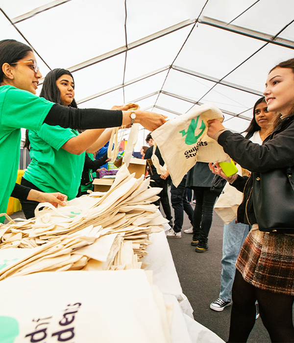 a student staff member handing out guild tote bags