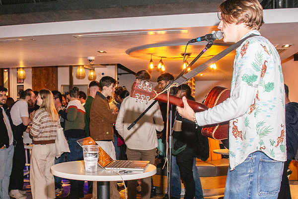 a singer with guitar at a postgraduate mixer