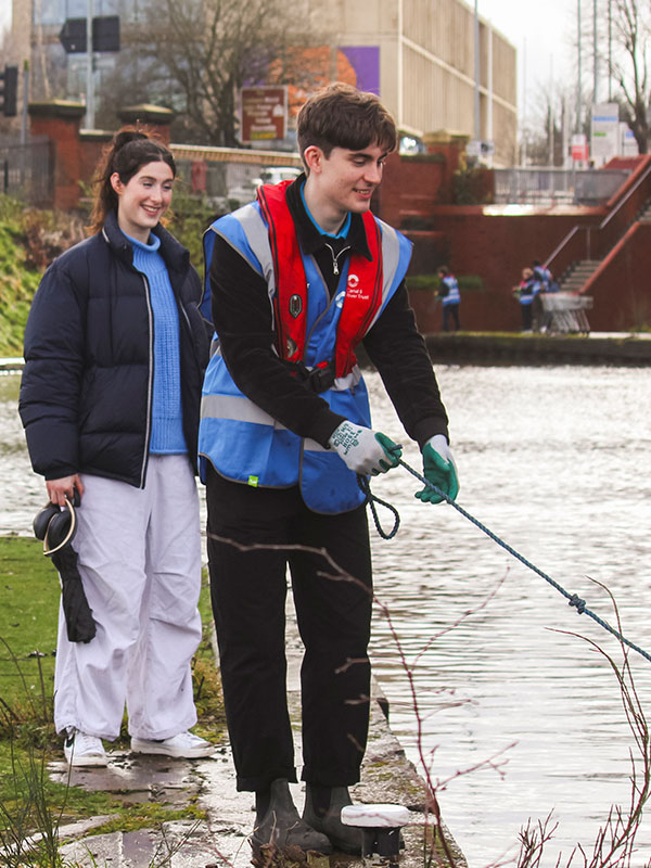 a picture of students picking litter out of a lake